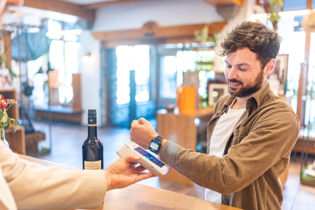 Mobiles Bezahlen für eine Weinflasche mit der Smartwatch am Bezahlterminal.