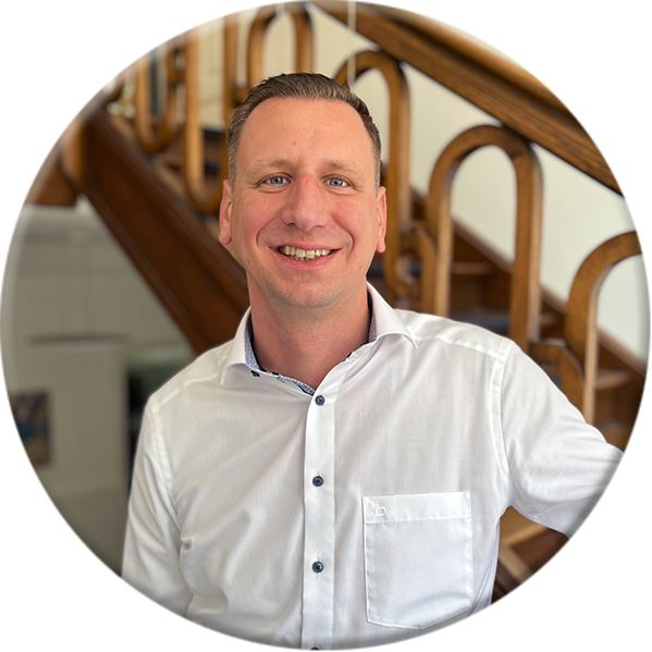 Foto von Nicolas Hils bei der First Cash Solution GmbH, schaut lächelnd in die Kamera.